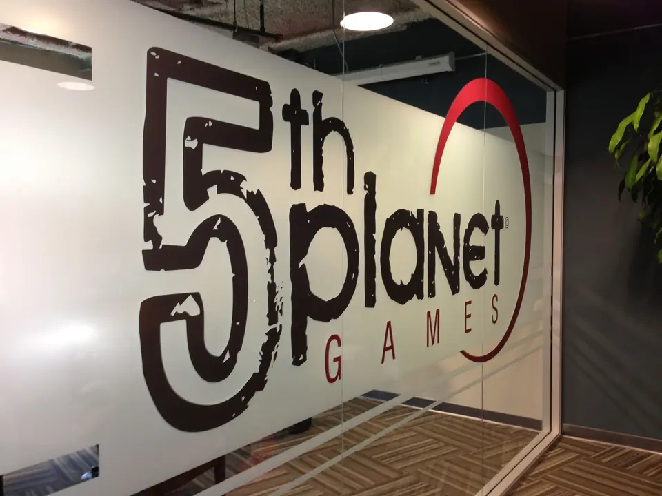 Large 5th Planet Games logo on a glass office wall